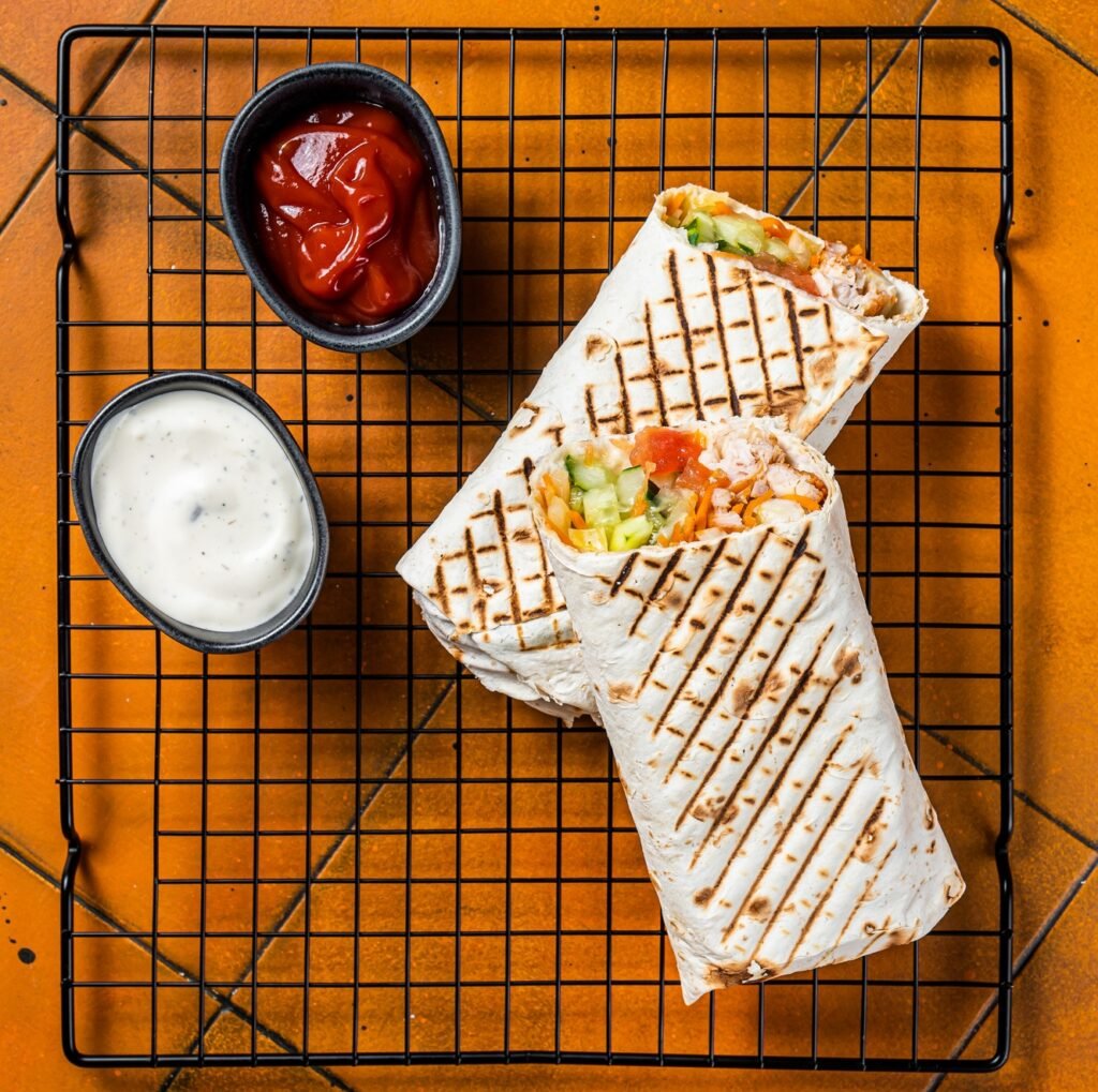 Shawarma durum doner kebab with meat and vegetable salad. Orange background. Top view